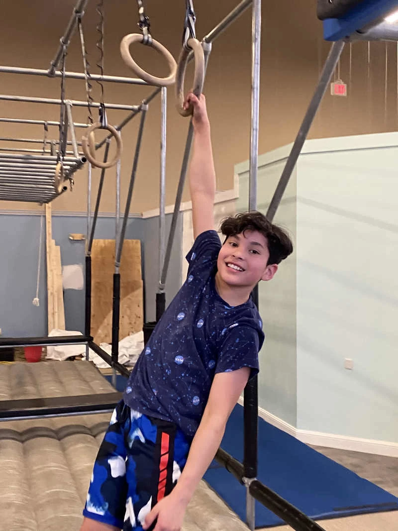 Boy ninja hanging from ninja rings